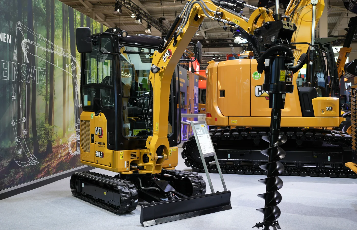 Compact excavator displayed with a hydraulic auger drive and earth-drilling bit