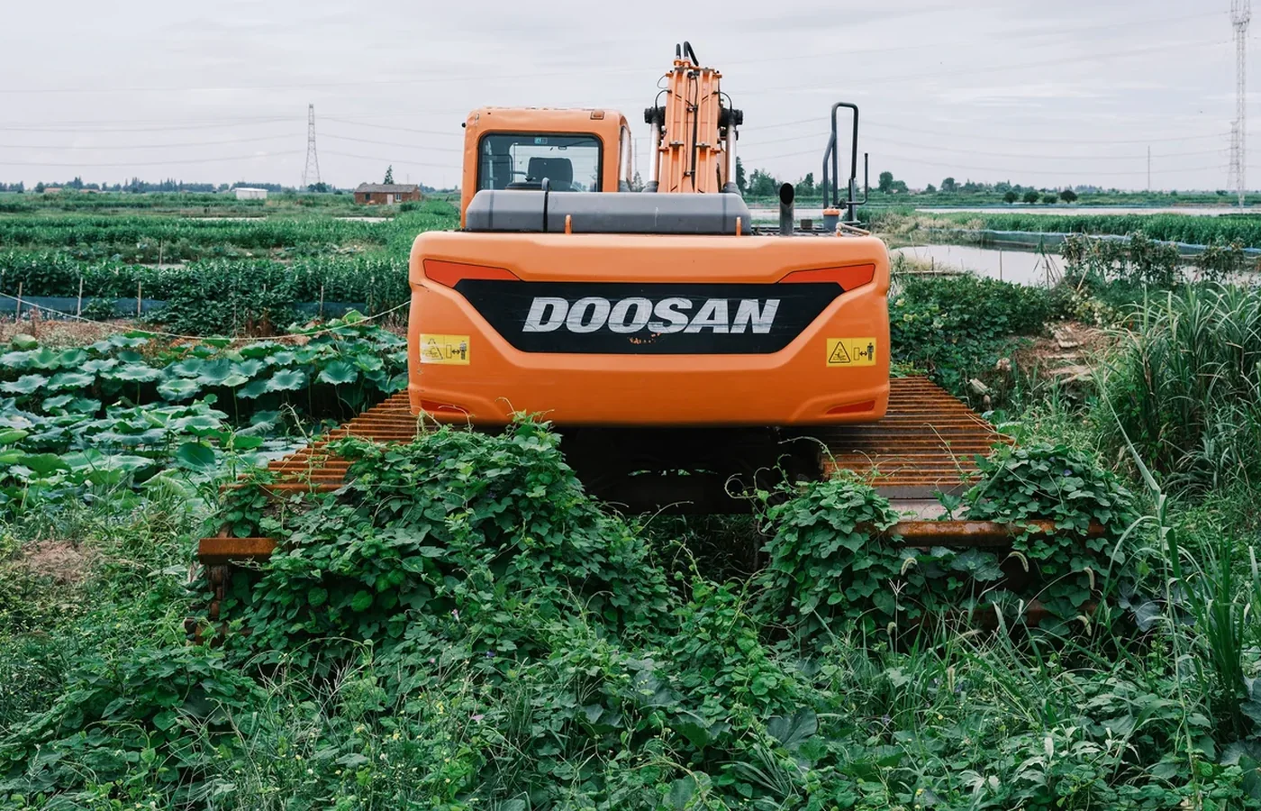 Tracked excavator positioned on a landscaped earthwork site where augers may be used for planting or posts