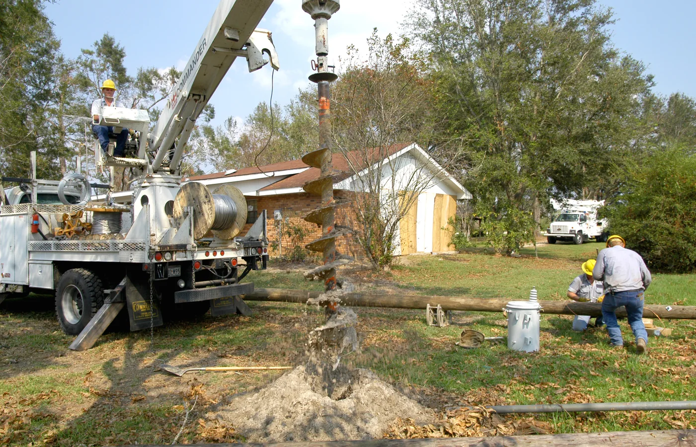 Utility crew using a truck-mounted auger to drill a hole for a replacement pole