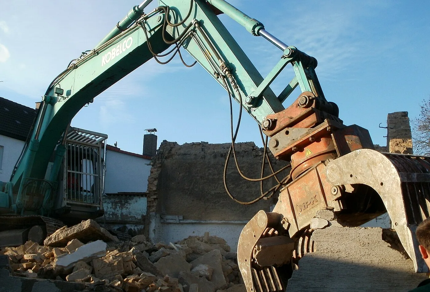 Rotating demolition grapple holding a heavy concrete block on a building demolition site