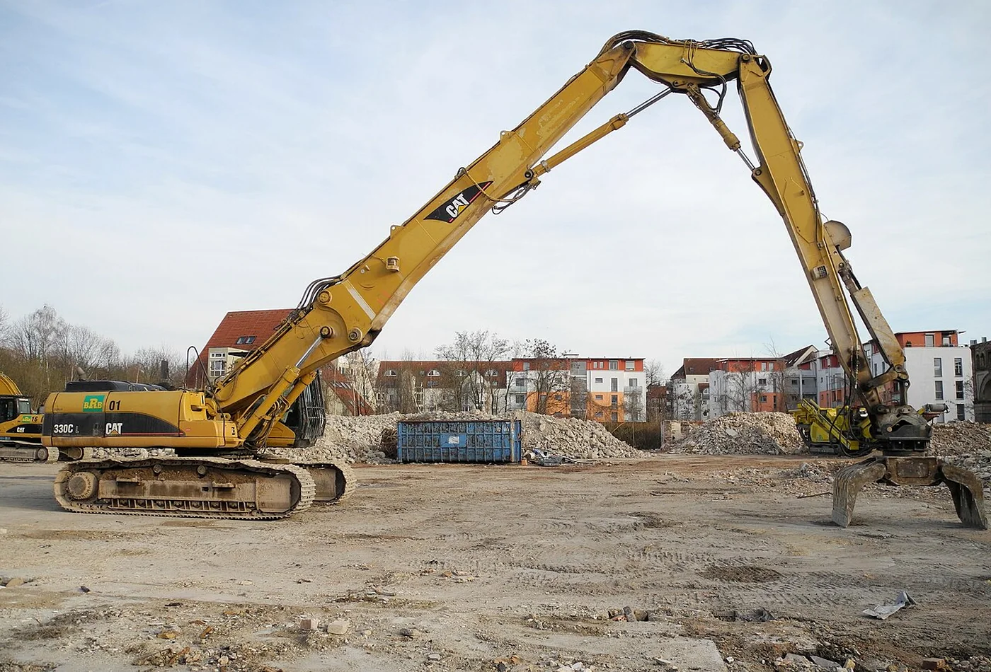 Long-reach tracked excavator fitted with demolition grapple on a cleared site