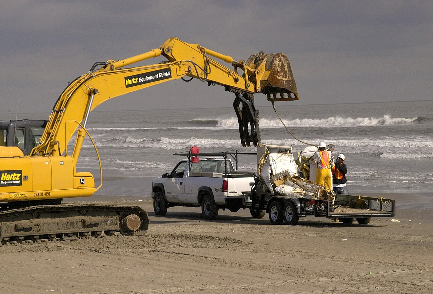 Excavator handling mixed debris during a controlled recovery and loading operation