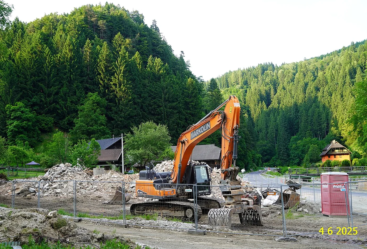 Excavator with grapple working on a rural building demolition site