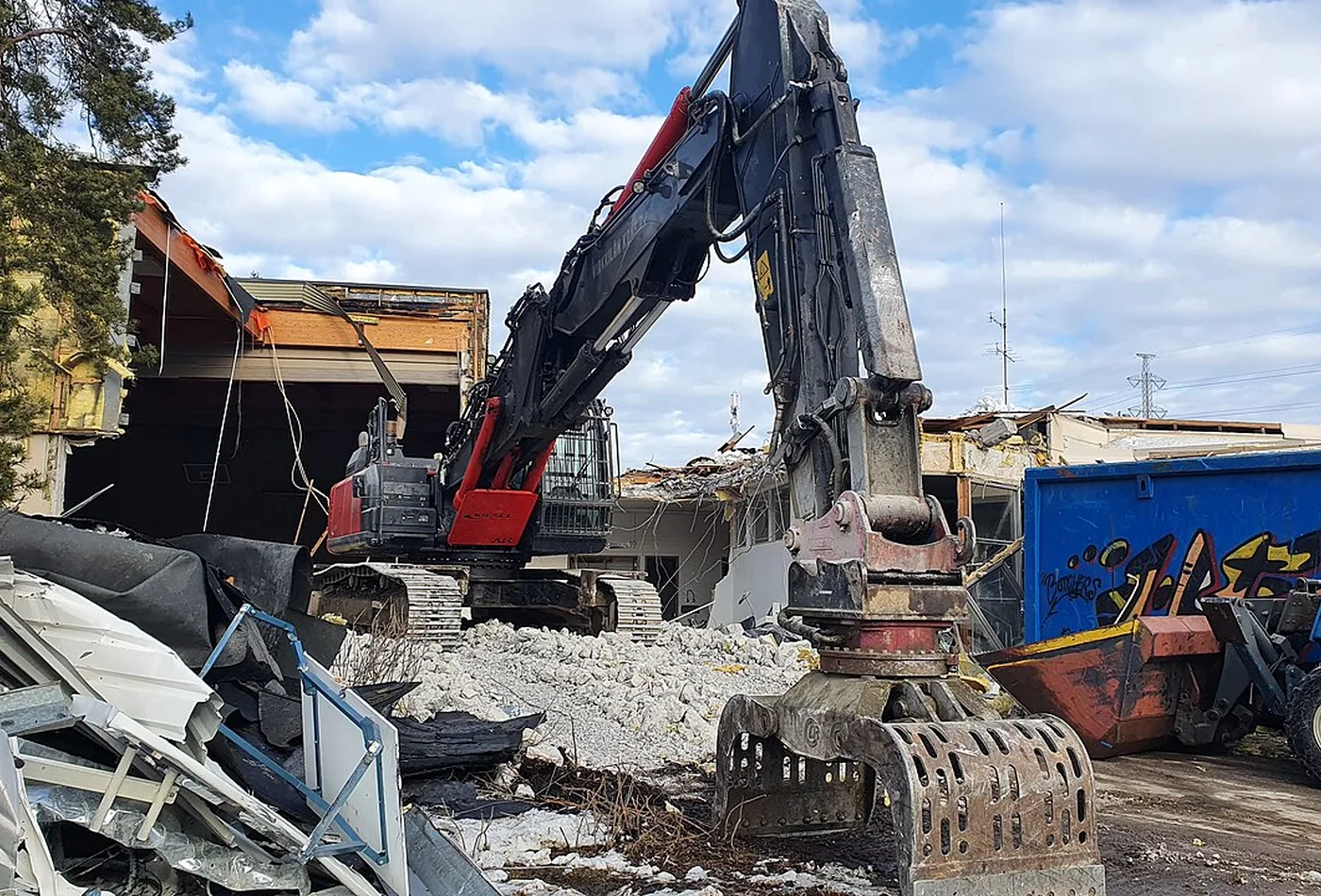 Large demolition grapple working among mixed sheet material and concrete during site clearance