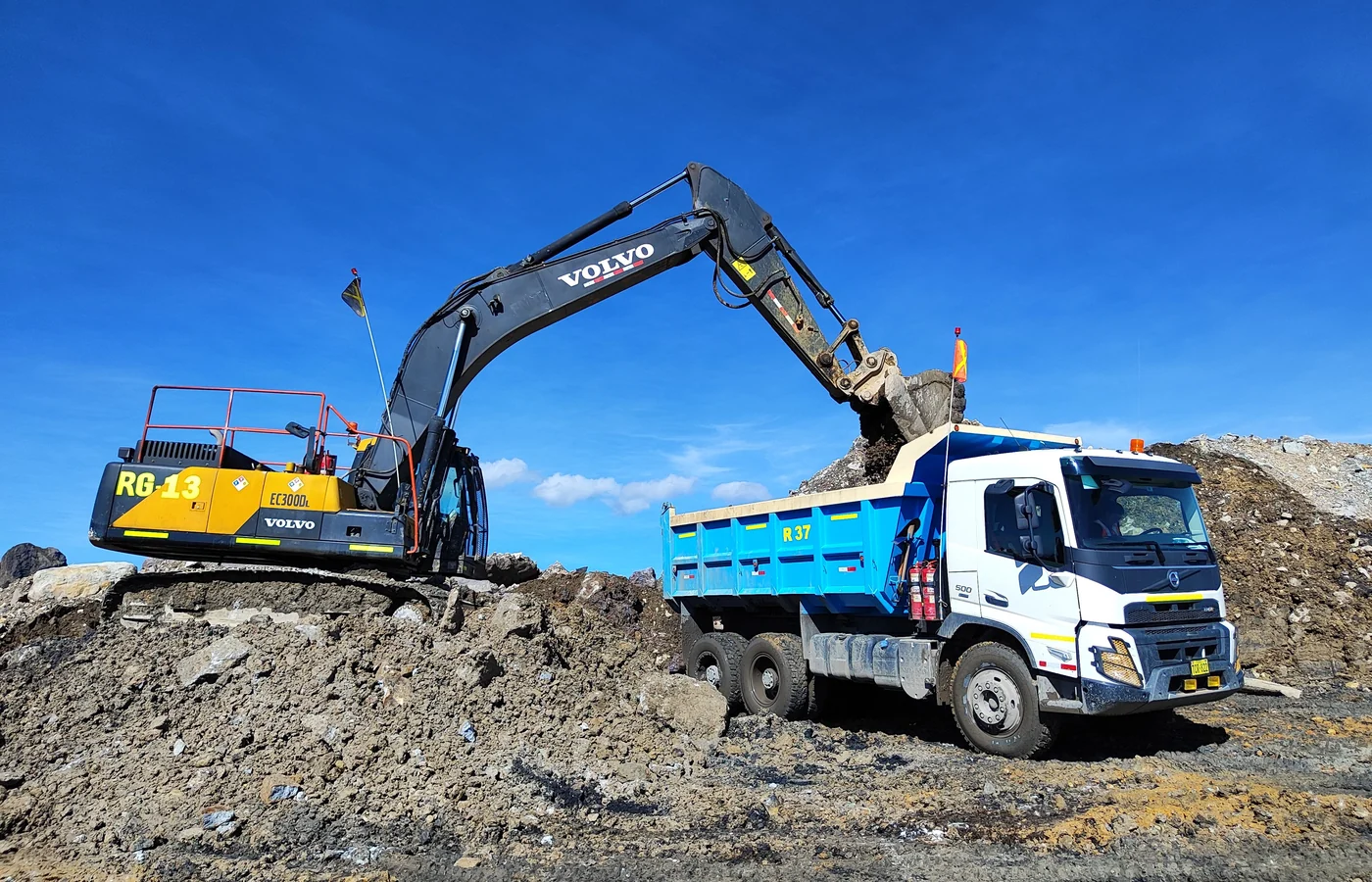 Excavator using a digging bucket to load excavated material into a dump truck