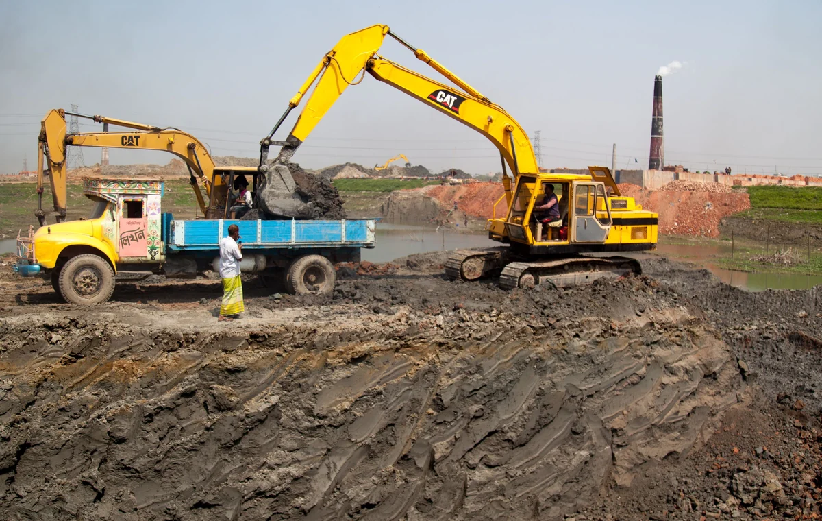Excavator loading wet excavated material into a site truck