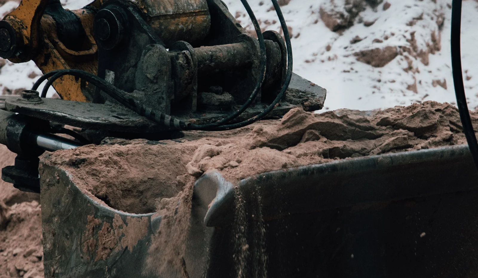 Close-up of an excavator bucket, linkage, hydraulic lines and pivot points