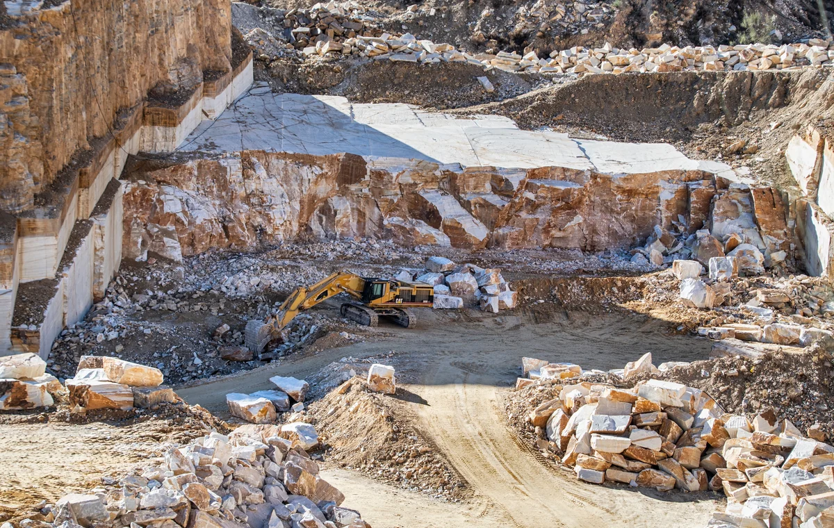 Tracked excavator operating in a stone quarry with rocky terrain