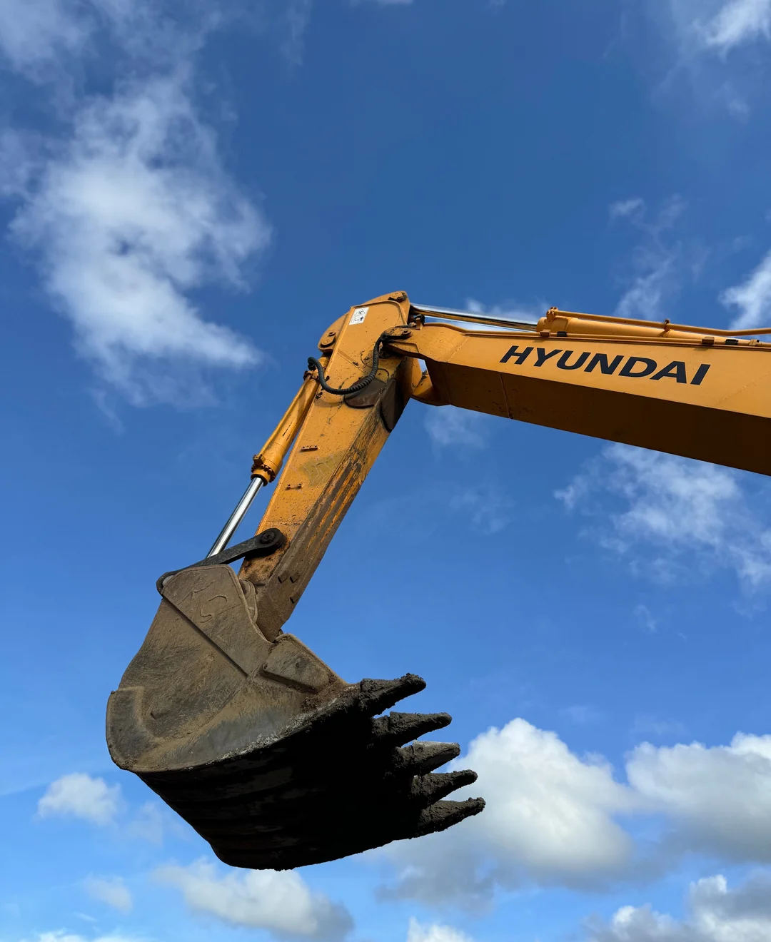 Excavator boom and digging bucket viewed against a blue sky