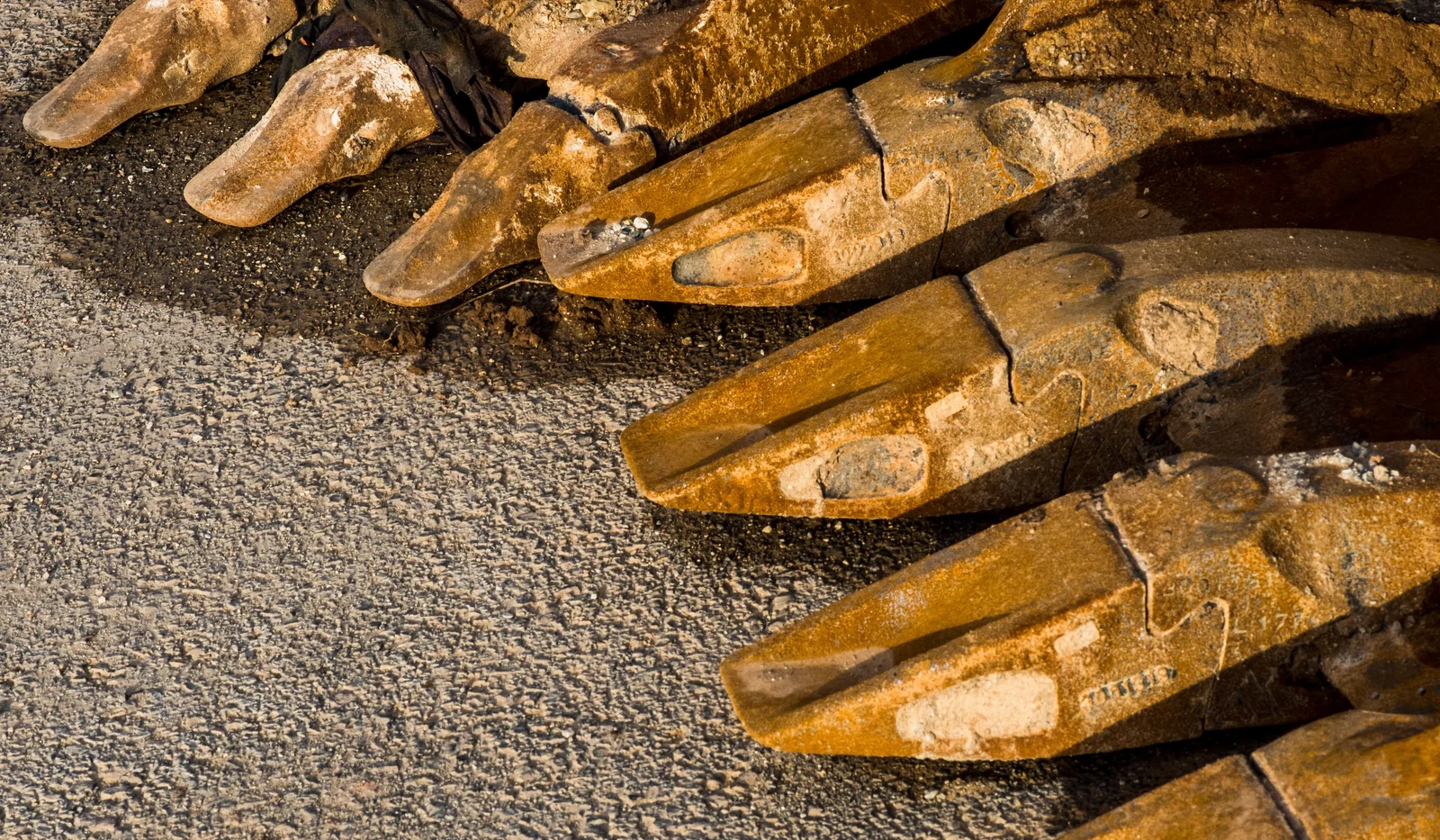 Close-up of worn excavator bucket teeth and adapters