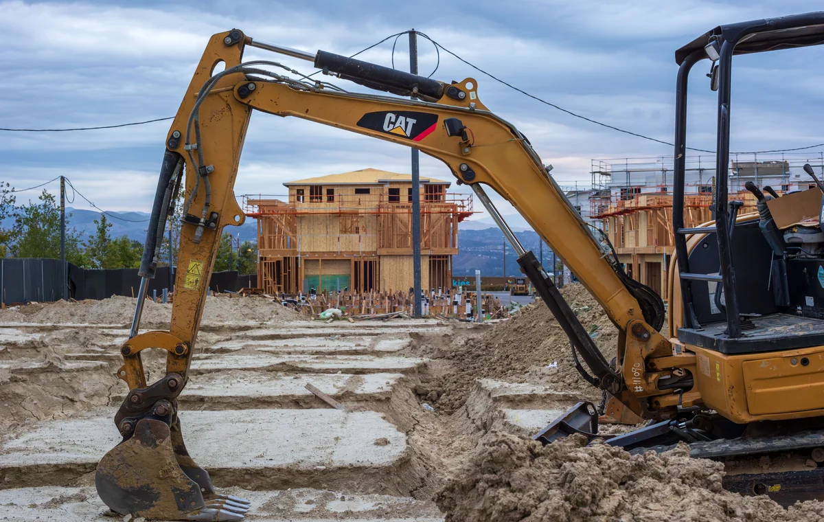 Compact excavator working around foundation excavations on a building site