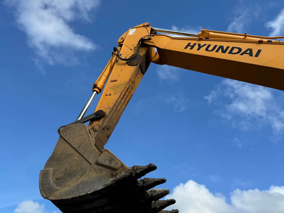 Excavator boom, linkage and bucket viewed against a blue sky