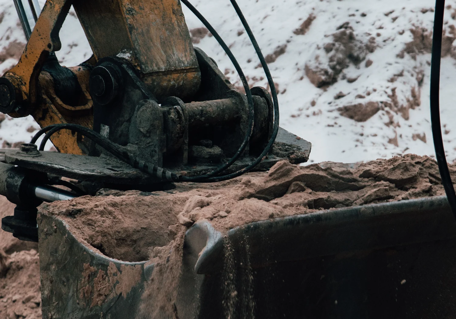 Close-up of a wide hydraulic tilt bucket carrying sand