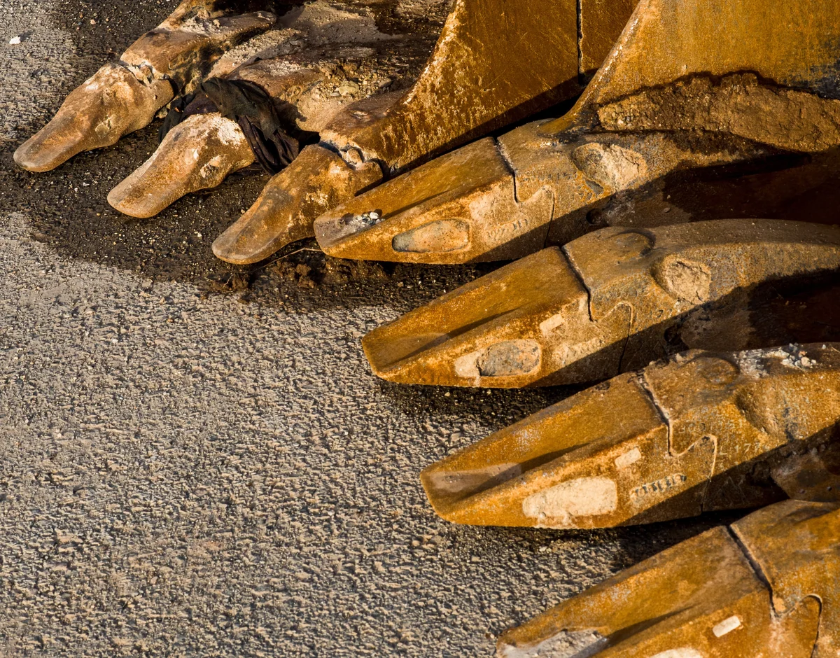 Close-up of used excavator bucket edges and wear components