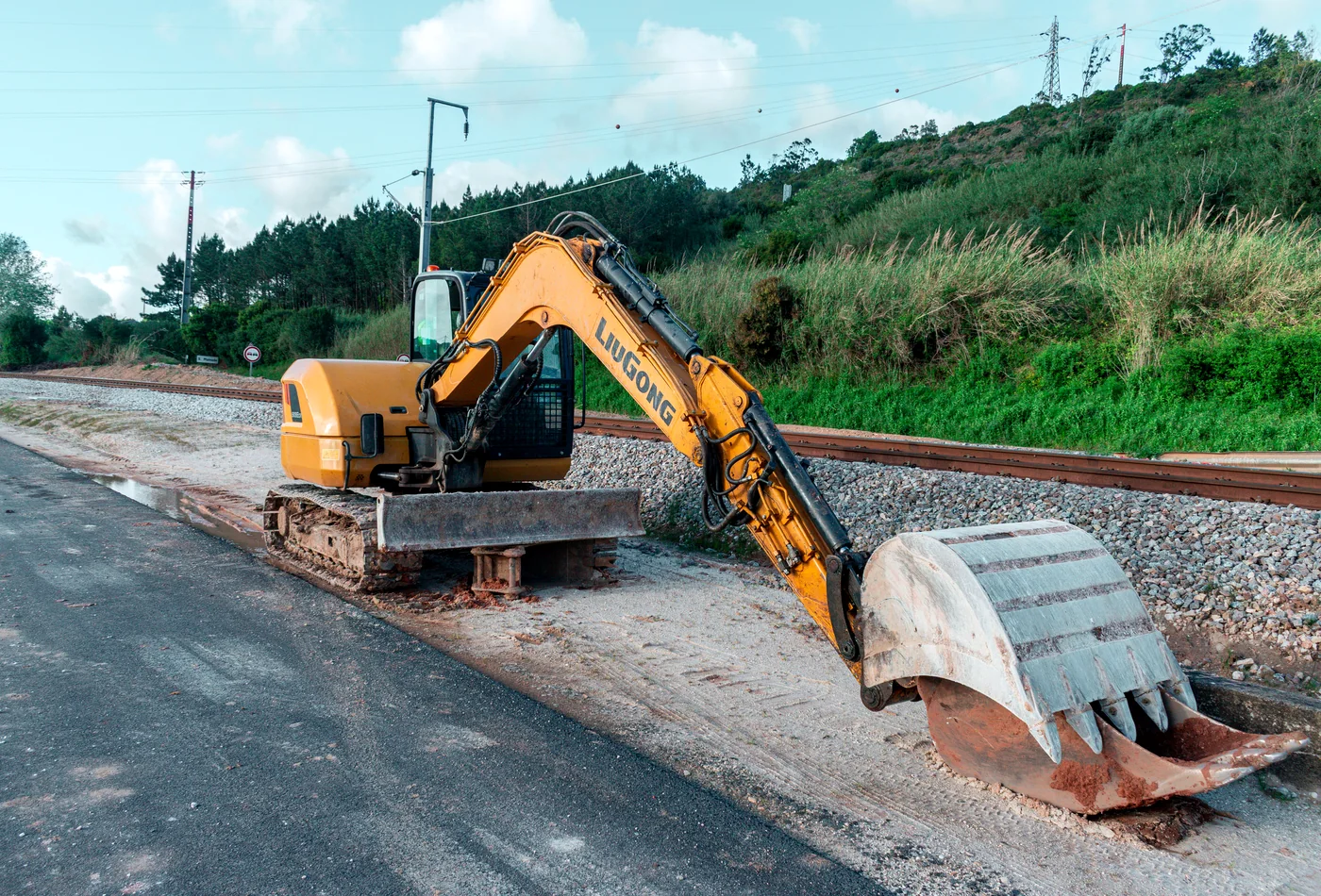 Tracked excavator beside a railway aggregate bed, illustrating gravel and graded material work