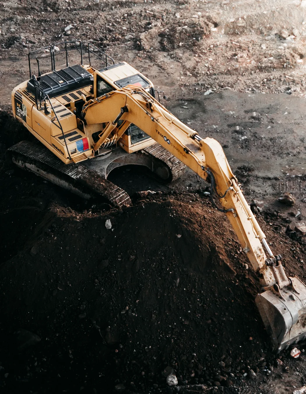 Aerial view of a tracked excavator processing a soil stockpile, illustrating working radius and stability