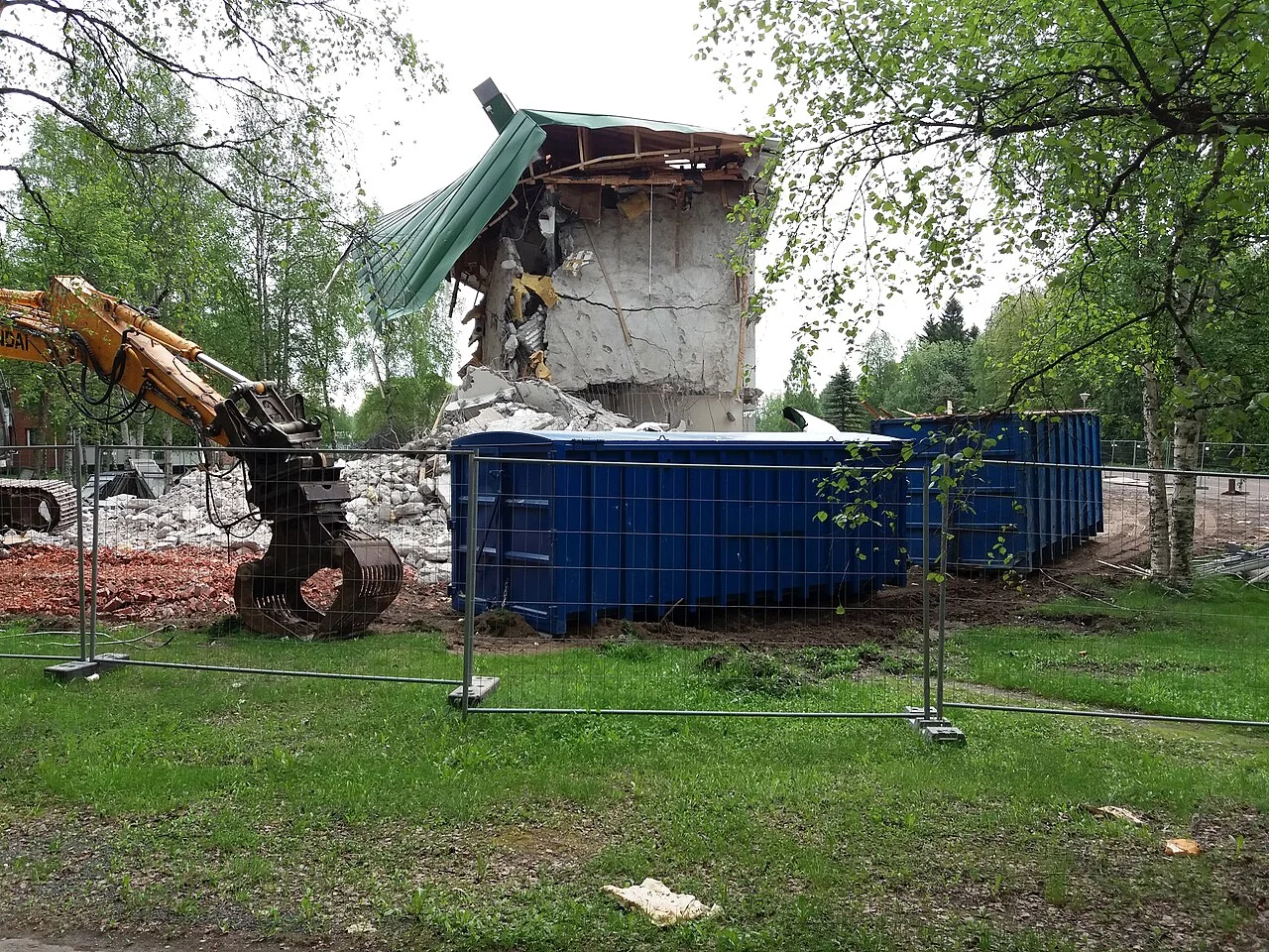 Compact excavator and sorting grapple working beside a demolition container