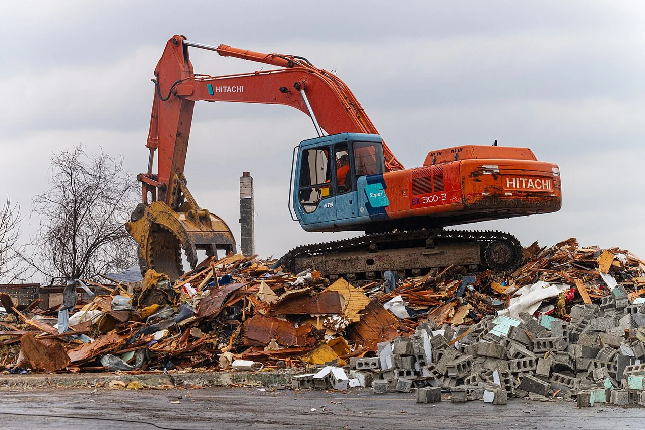Excavator working on a pile of mixed timber, block and demolition debris