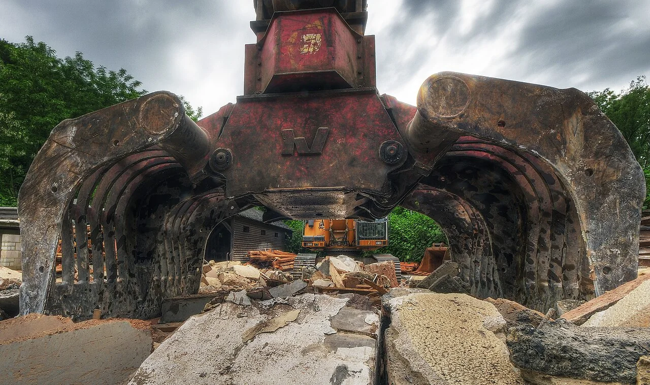 Low-angle close-up through the open shells of a worn demolition sorting grapple