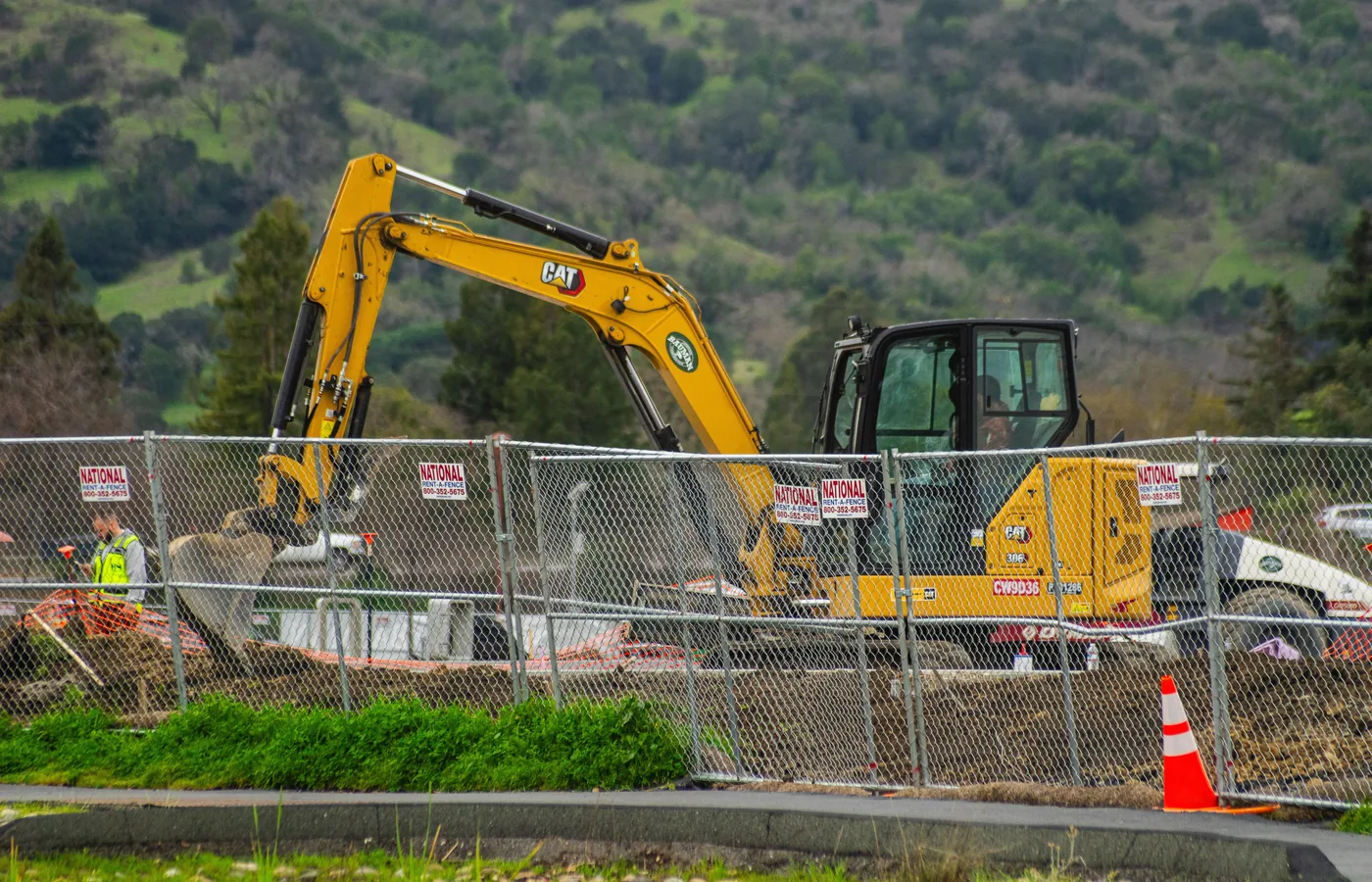 Excavator operating within a fenced and signed work area