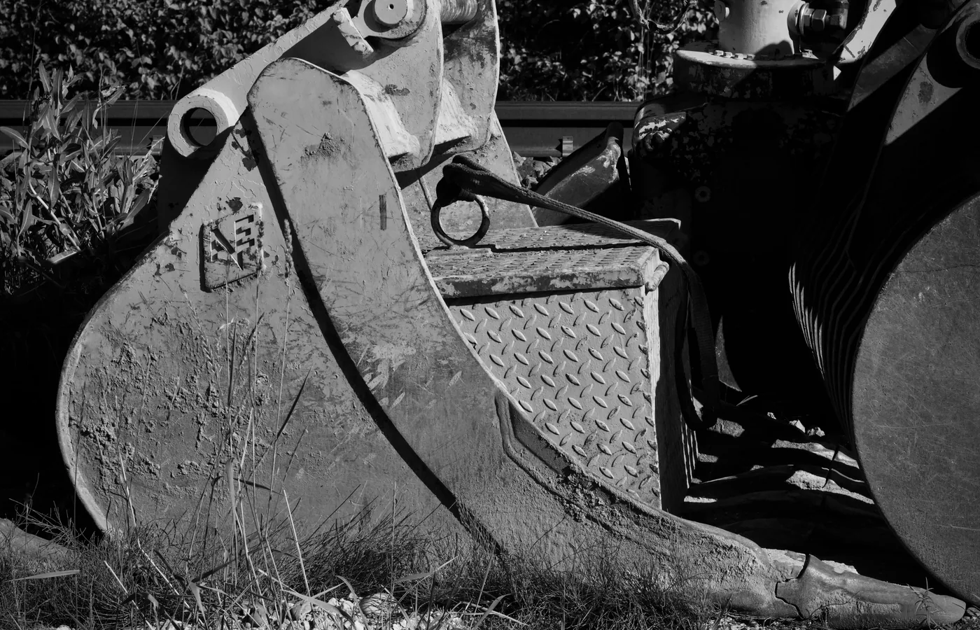 Close-up of excavator bucket linkage, coupler and worn steel surfaces