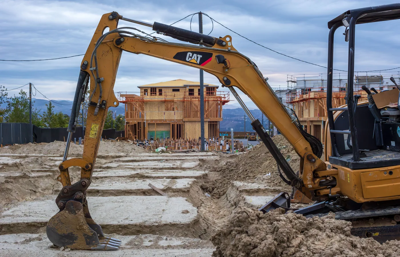 Compact excavator digging around a residential building foundation