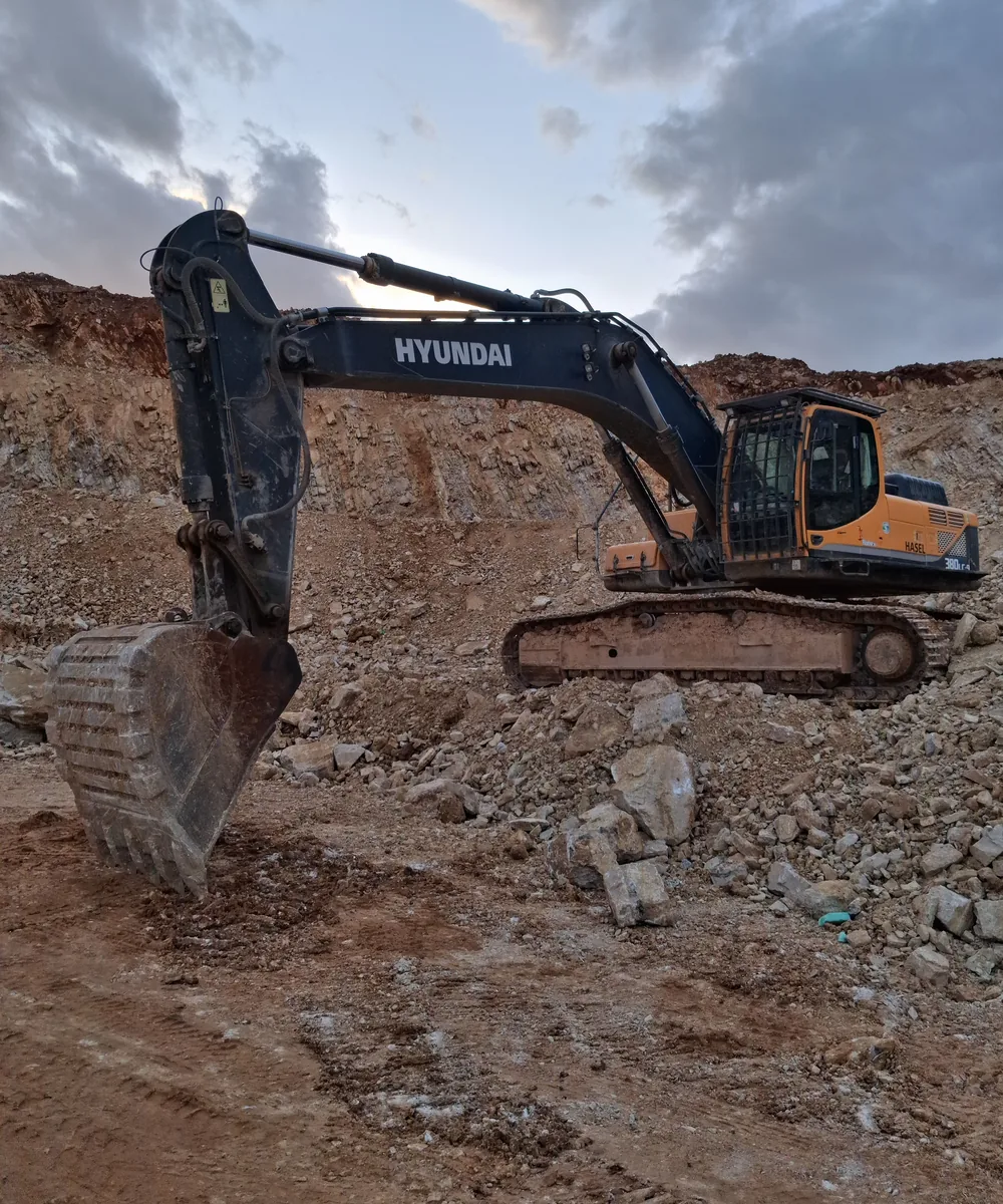 Large excavator working in rocky ground with a reinforced bucket